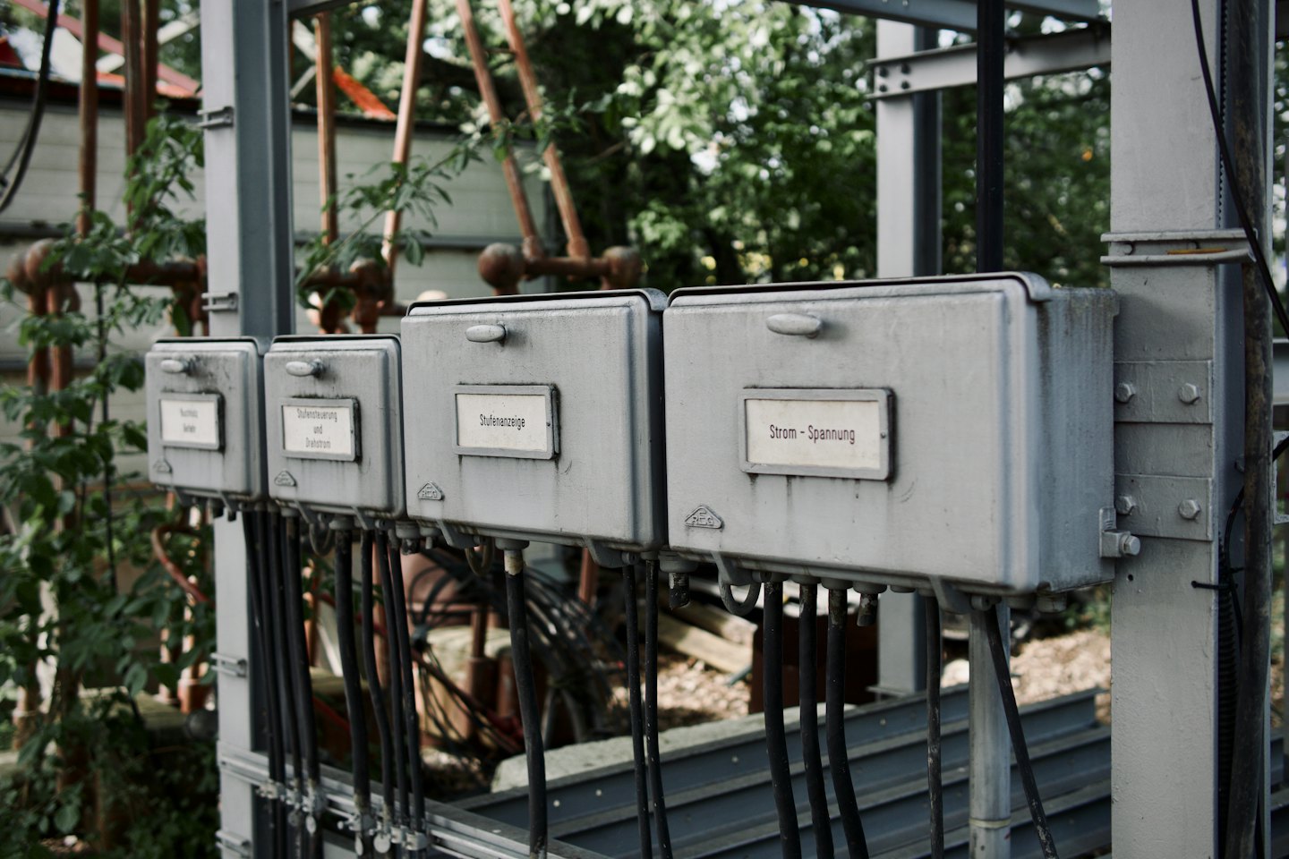 Weathered electrical control boxes mounted on metal frame.